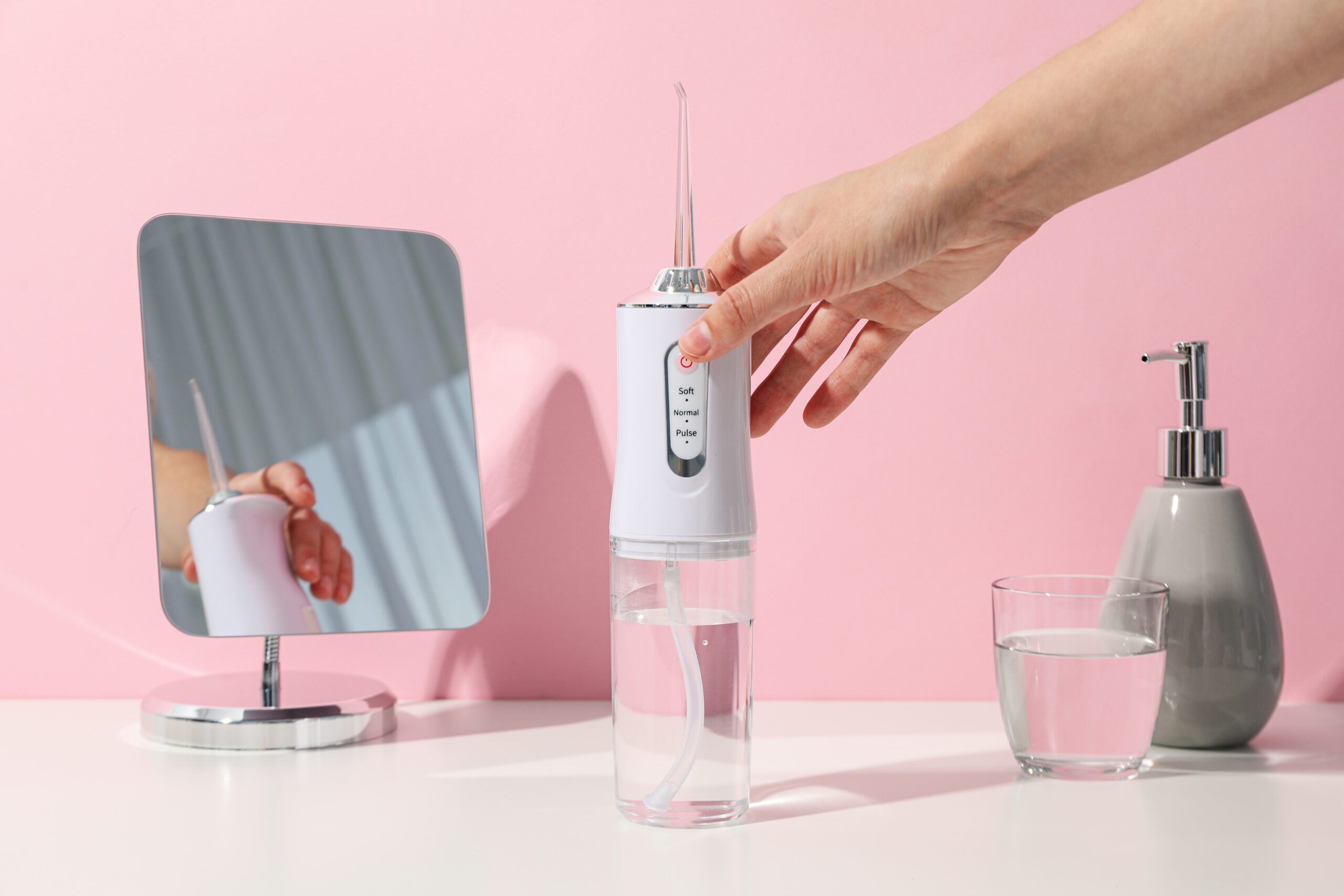 جهاز خيط الاسنان المائي موضوع على طاولة بجانب المرآة – فوائد خيط الاسنان المائي لصحة الفم