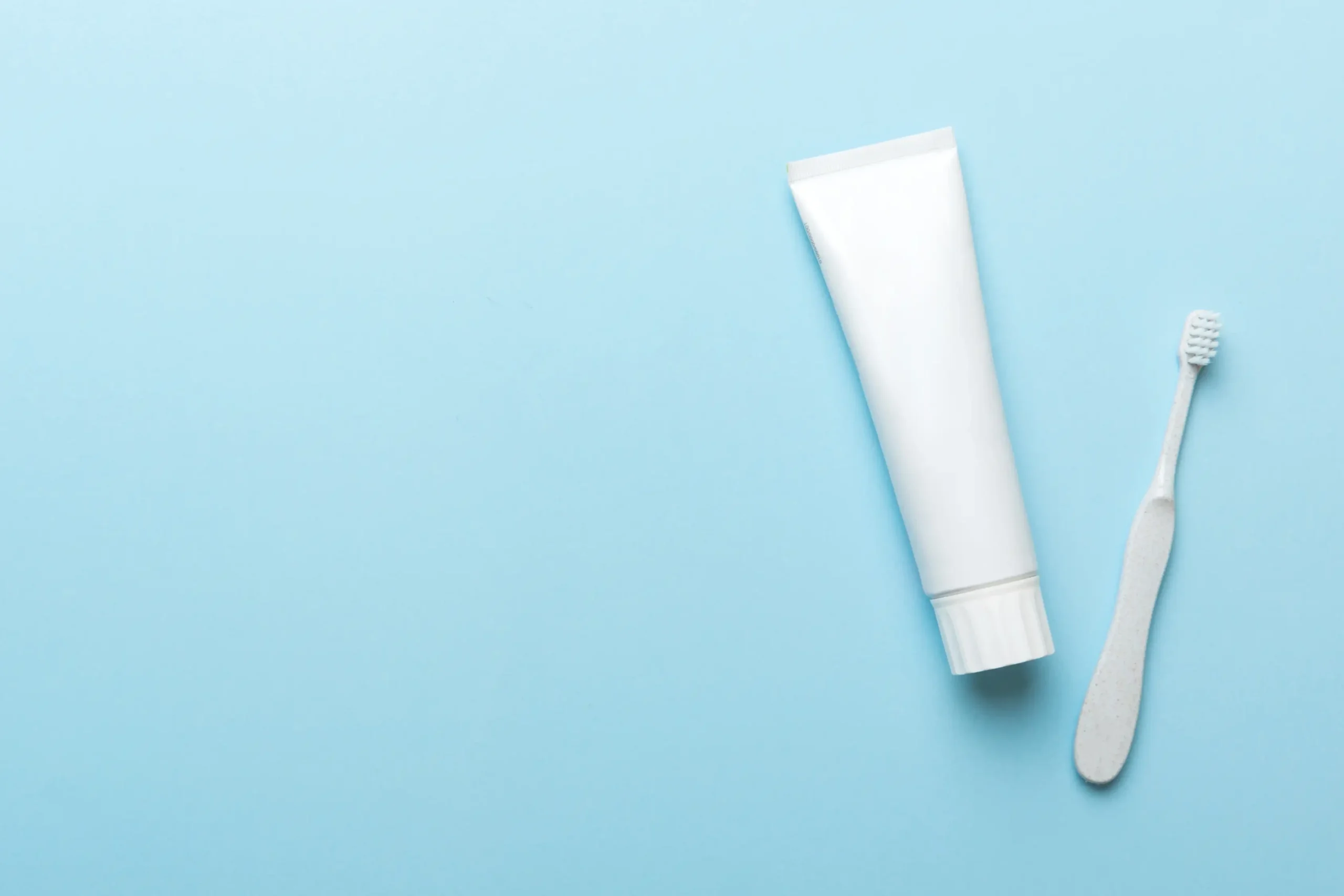 معجون أسنان مع فرشاة بيضاء على خلفية زرقاء - طرق تبييض الأسنان في المنزل