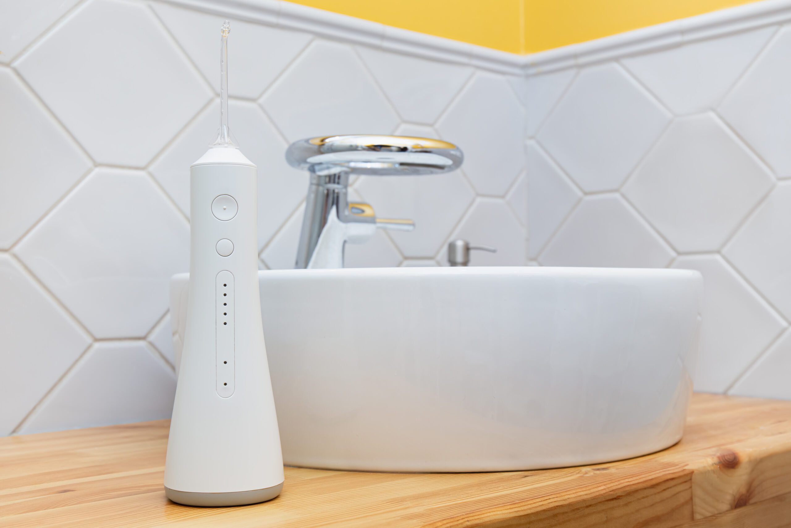 دليل شراء خيط الاسنان المائي - جهاز خيط مائي أبيض حديث على منضدة حمام خشبية